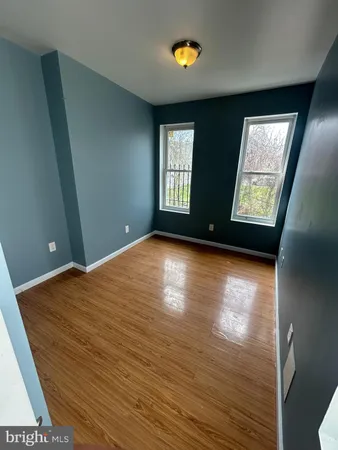 a view of empty room with window and wooden floor