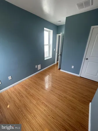 a view of empty room with window and wooden floor