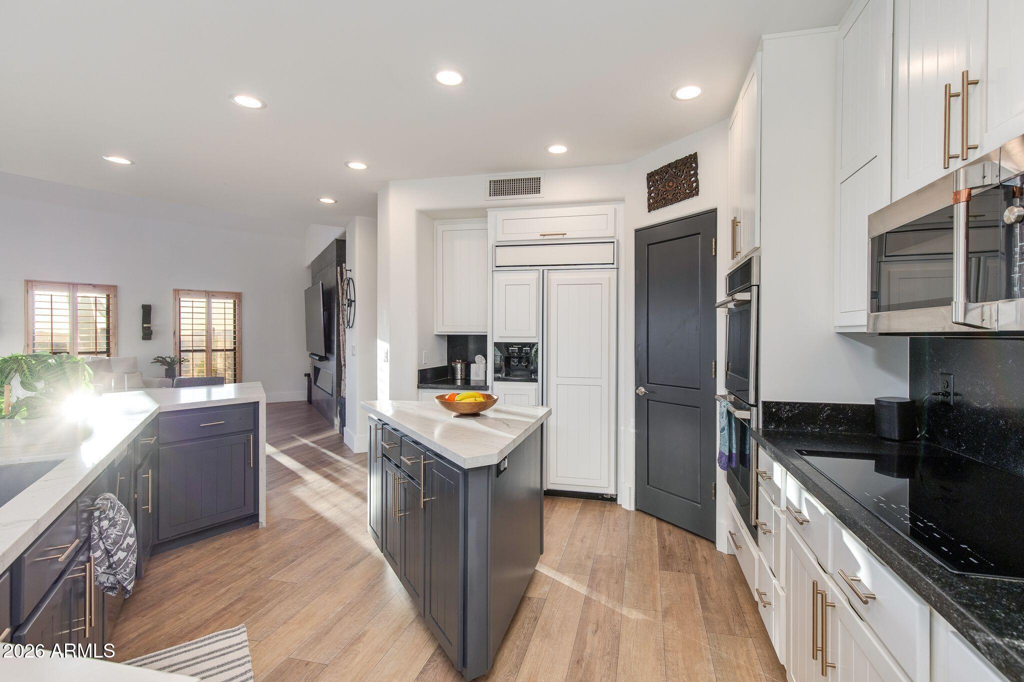 5901 East Restin Road Cave Creek, AZ 85331 - Photo 24 of 101 a kitchen with stainless steel appliances granite countertop a refrigerator a sink dishwasher a stove and a dining table with wooden floor