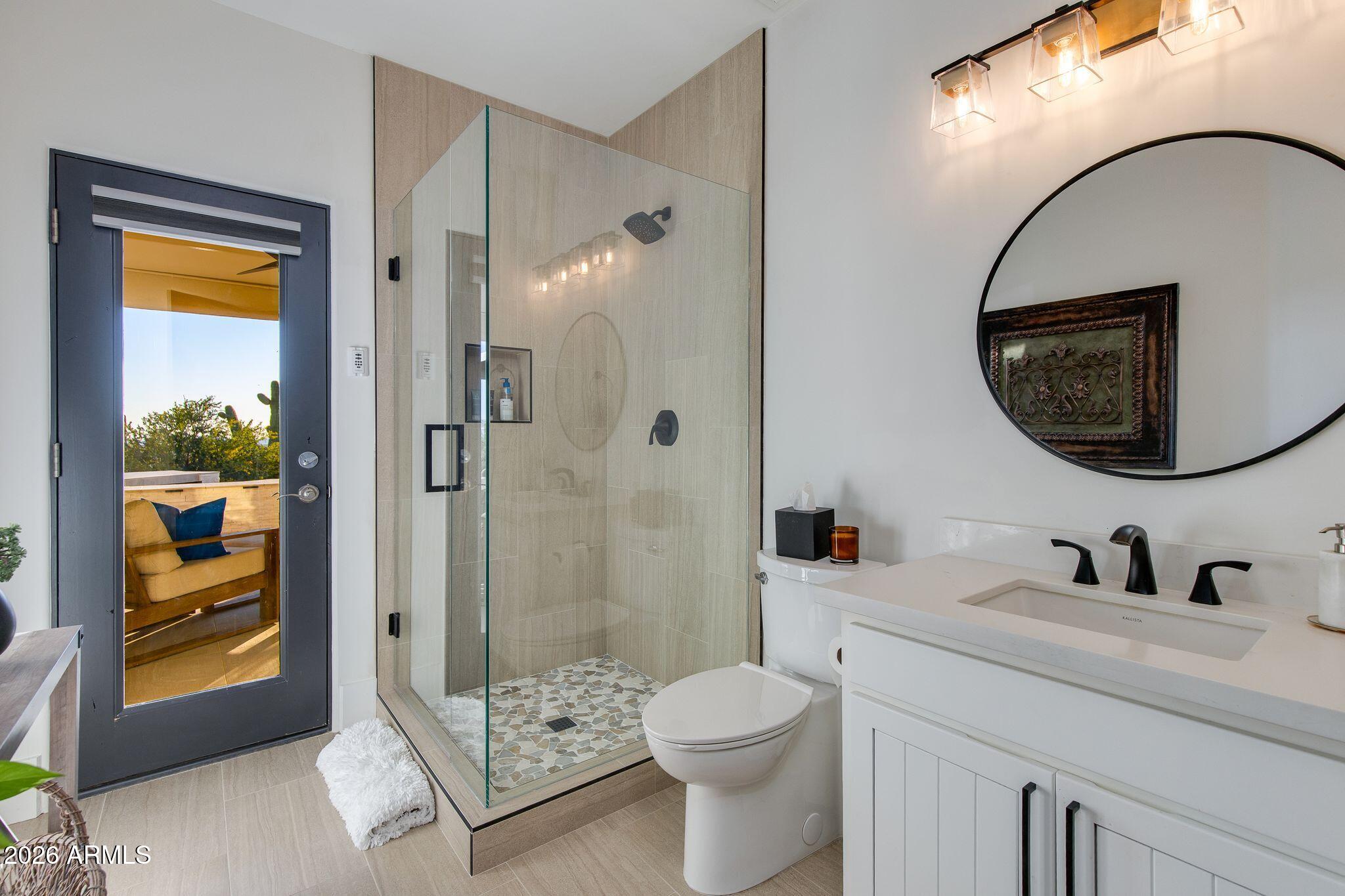 5901 East Restin Road Cave Creek, AZ 85331 - Photo 49 of 101 a bathroom with a toilet a sink a glass door a shower and a mirror