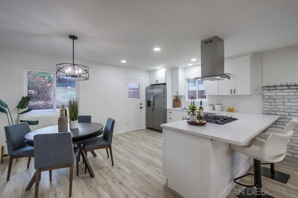 1839 Yettford Road Vista, CA 92083 - Photo 11 of 42 a kitchen with stainless steel appliances a dining table chairs and wooden floor