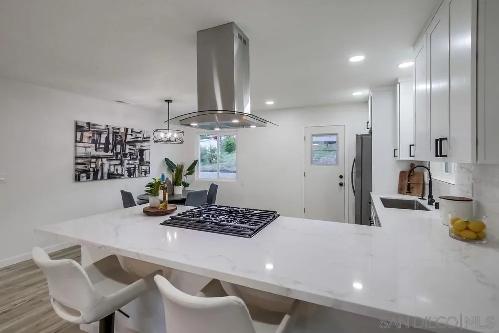 1839 Yettford Road Vista, CA 92083 - Photo 12 of 42 a kitchen with stainless steel appliances granite countertop a sink a stove white cabinets and chairs
