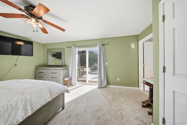 a bedroom with a bed ceiling fan and a wooden floor