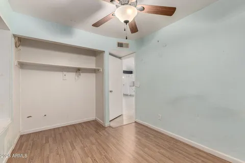 en empty room with wooden floor and fan