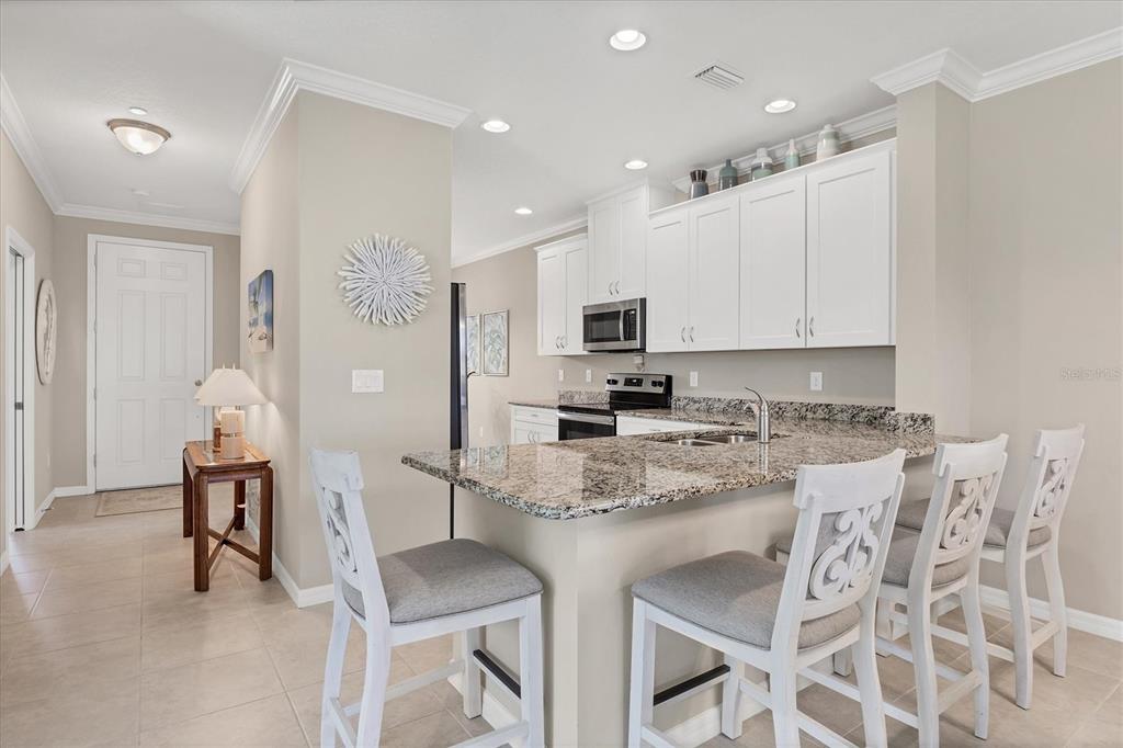13703 Messina Loop, Unit 104 Bradenton, FL 34211 - Photo 14 of 86 a kitchen with stainless steel appliances kitchen island granite countertop a table chairs sink and cabinets