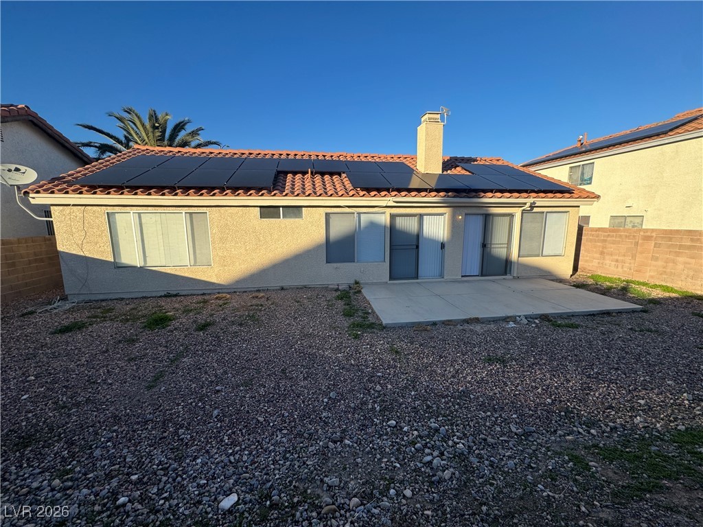 7447 Palermo Avenue Las Vegas, NV 89147 - Photo 18 of 26 Rear view of house featuring a fenced backyard, a chimney, a patio area, stucco siding, and solar panels