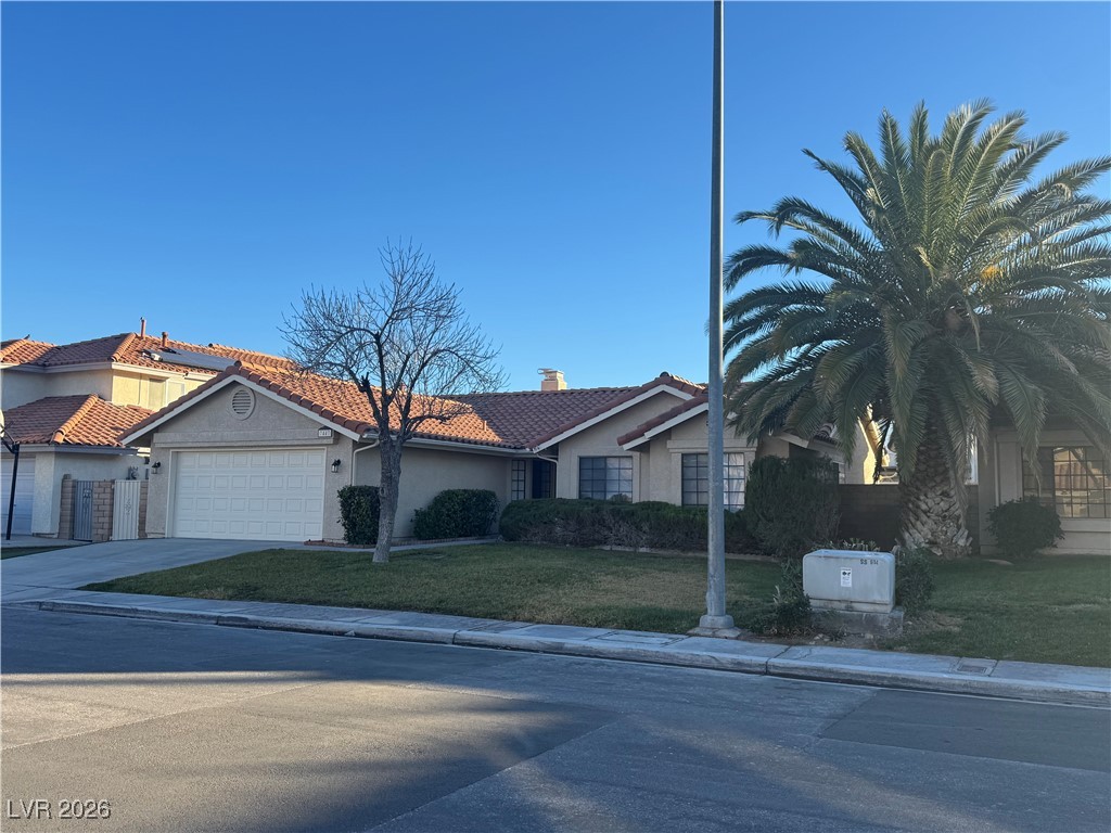 7447 Palermo Avenue Las Vegas, NV 89147 - Photo 2 of 26 View of front facade featuring a front yard, stucco siding, a tile roof, driveway, and an attached garage