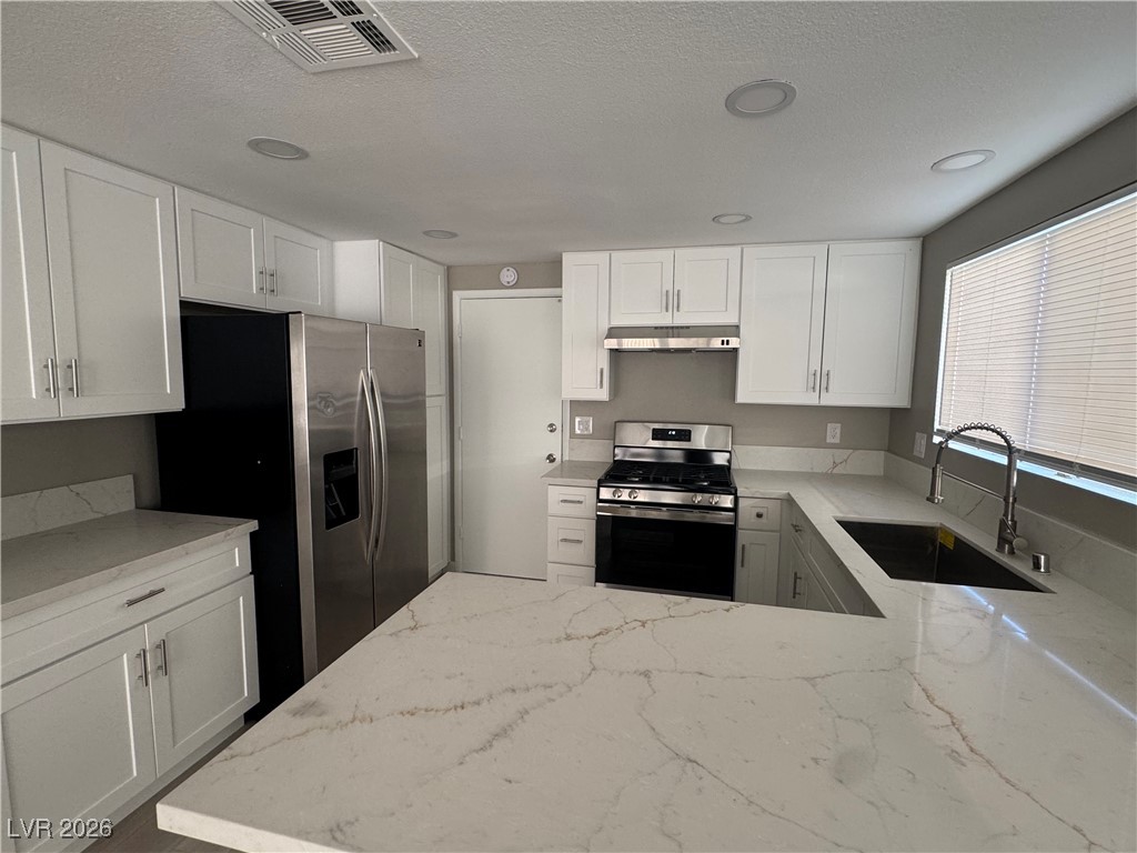 7447 Palermo Avenue Las Vegas, NV 89147 - Photo 7 of 26 Kitchen featuring stainless steel appliances, light stone counters, white cabinets, under cabinet range hood, and recessed lighting