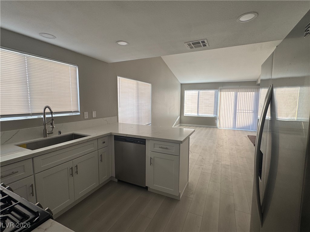 7447 Palermo Avenue Las Vegas, NV 89147 - Photo 26 of 26 Kitchen featuring appliances with stainless steel finishes, vaulted ceiling, a peninsula, light wood finished floors, and open floor plan