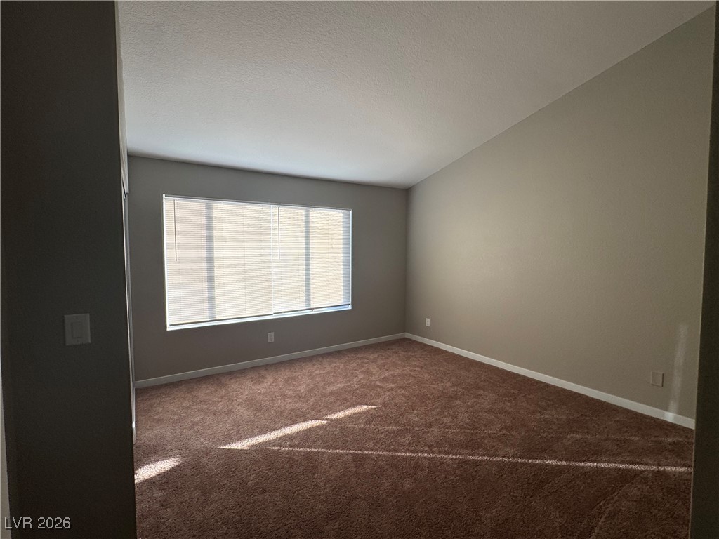 7447 Palermo Avenue Las Vegas, NV 89147 - Photo 8 of 26 Primary Bedroom with dark colored carpet, a textured ceiling, and lofted ceiling