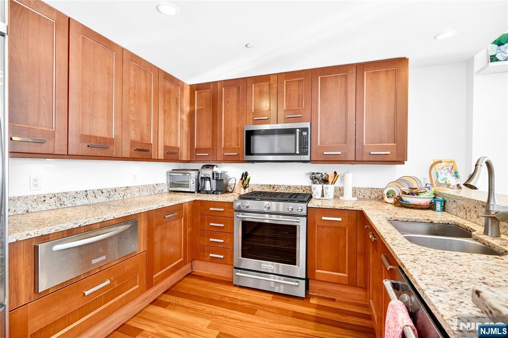 8100 River Road, Unit 801 North Bergen, NJ 07047 - Photo 23 of 48 a kitchen with stainless steel appliances granite countertop a stove top oven a sink dishwasher and a microwave oven with wooden cabinets