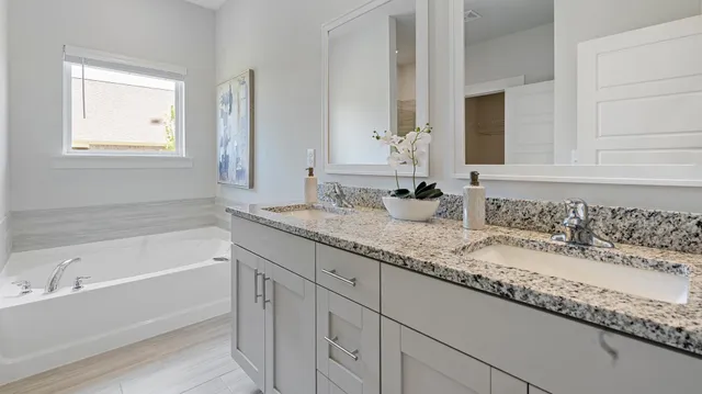 a bathroom with a granite countertop bathtub a sink and a window