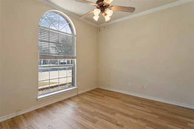an empty room with wooden floor chandelier fan and windows