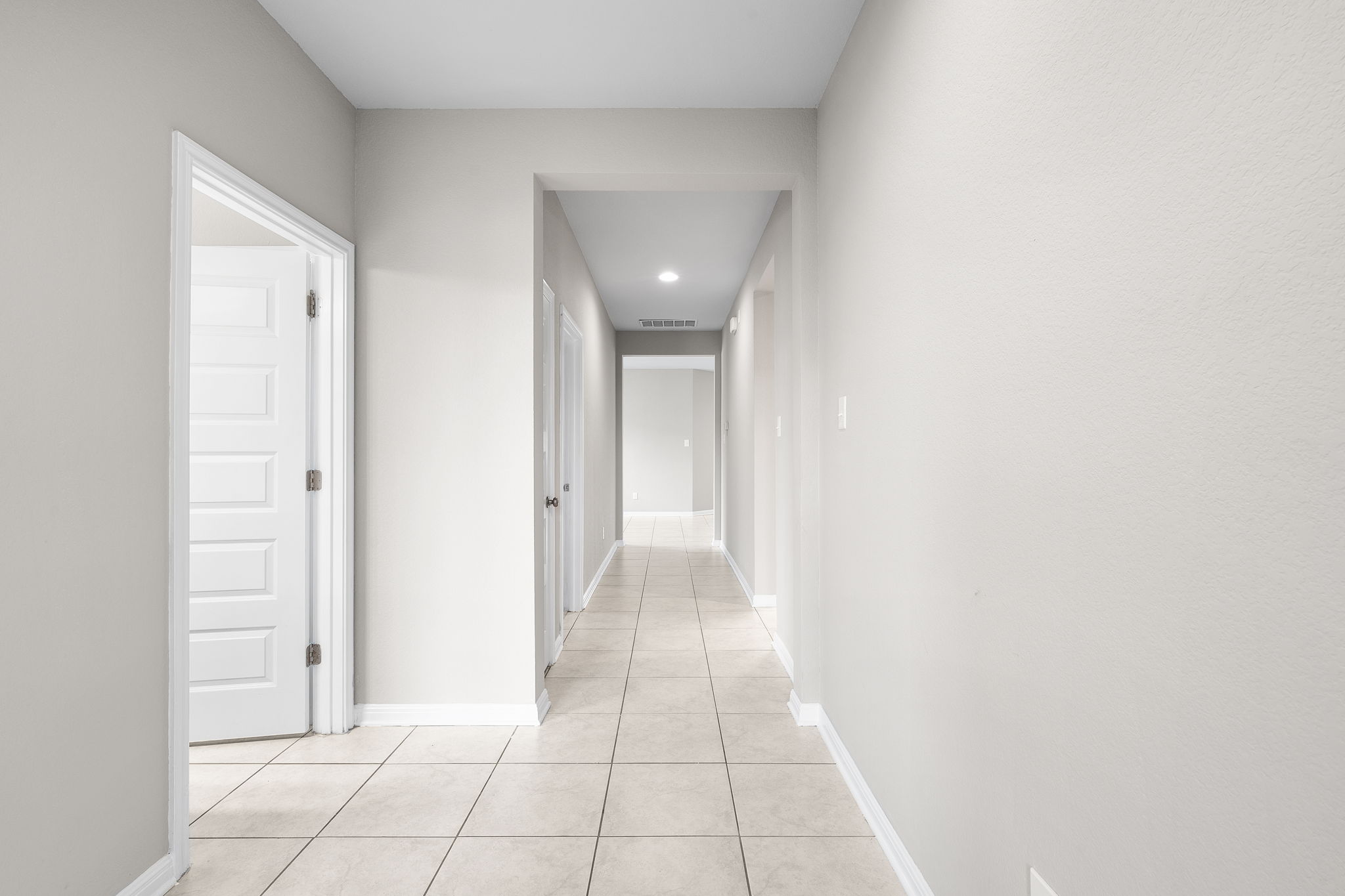 313 Mclintock Road Jarrell, TX 76537 - Photo 4 of 40 A well-lit interior hallway features tiled flooring and clean lines, guiding the eye through the home.