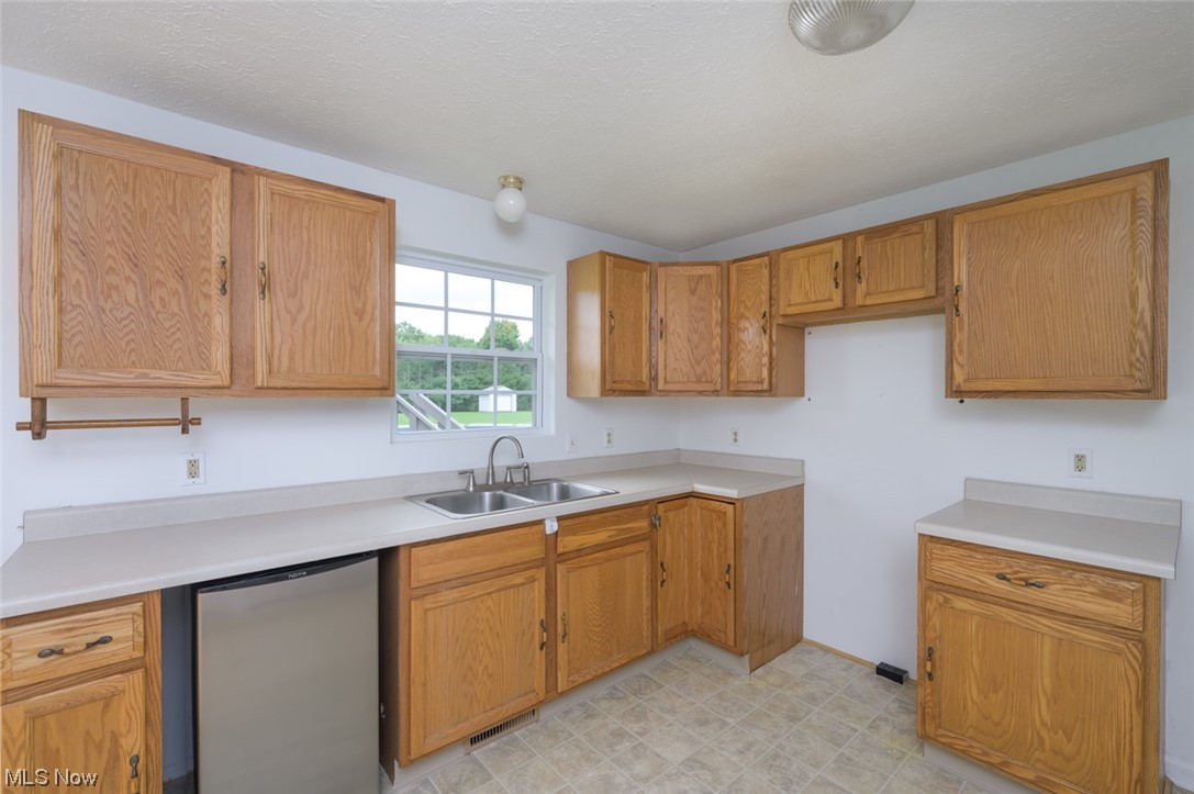 8045 State Rte 5 Ravenna, OH 44266 - Photo 18 of 32 Kitchen featuring stainless steel dishwasher, brown cabinets, light countertops, and light tile floors