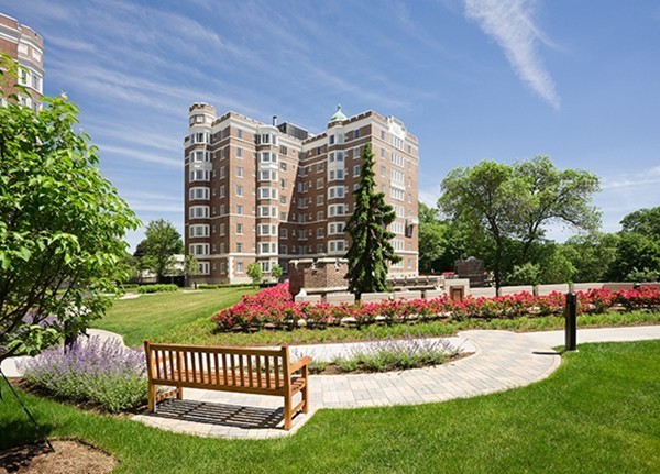 a front view of multi story residential apartment building with yard and sign board