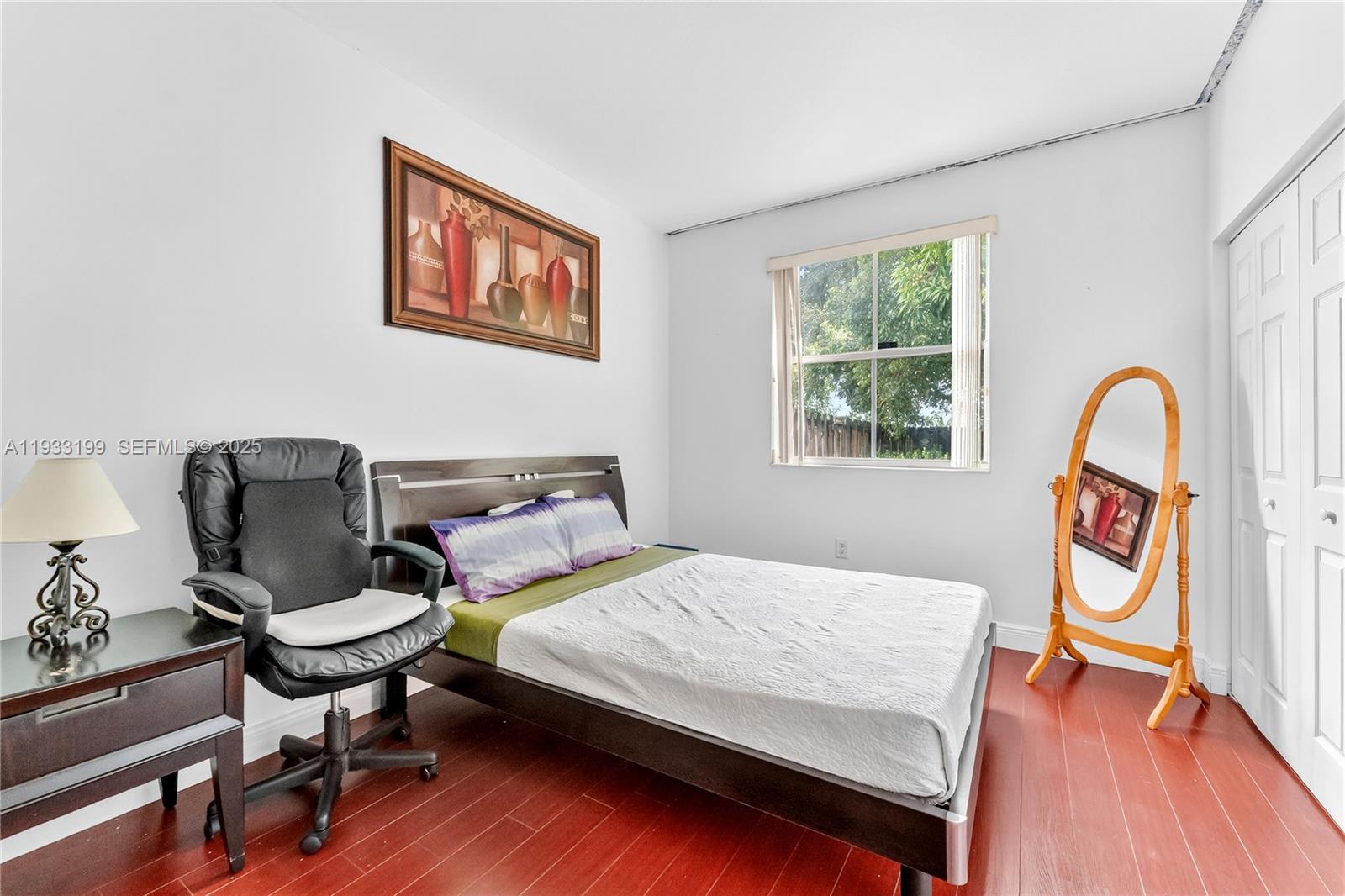 10934 Southwest 247th Terrace Homestead, FL 33032 - Photo 10 of 28 a bedroom with a bed and a bookshelf with wooden floor