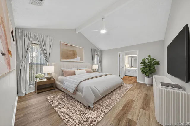 a bedroom with a large bed and a flat tv screen on dresser