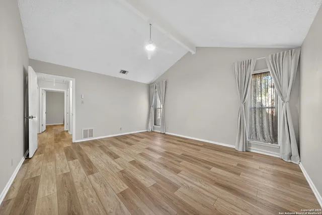 a view of empty room with wooden floor and fan