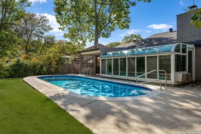 a view of a swimming pool with a sitting area and large trees