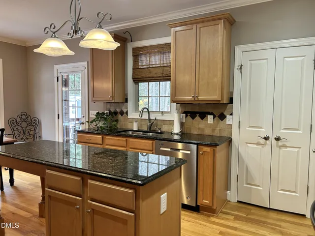 a kitchen with kitchen island granite countertop a sink cabinets and wooden floor