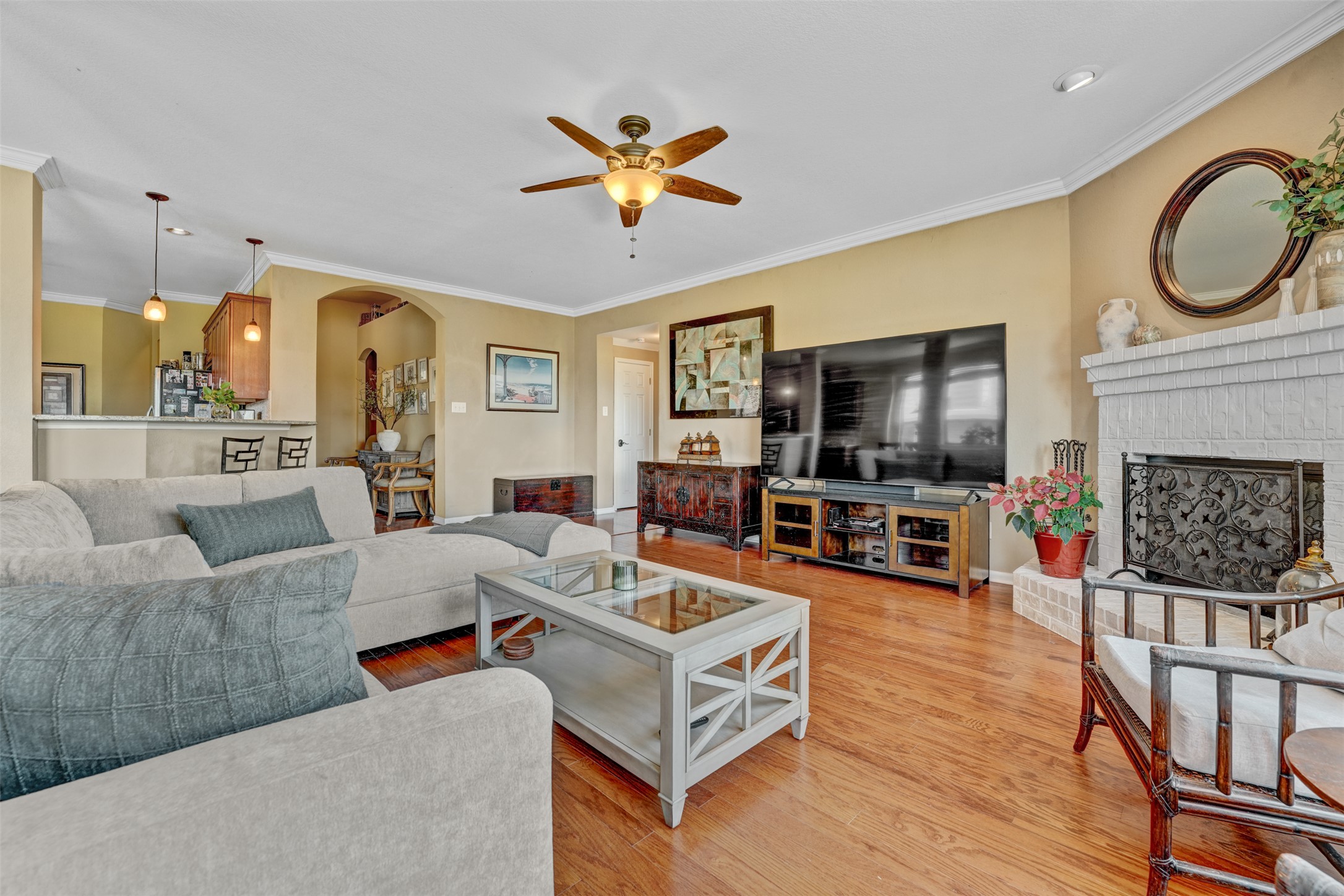 2521 Amen Corner Road Pflugerville, TX 78660 - Photo 5 of 40 Living area featuring wood-finish flooring, a white brick fireplace with a decorative screen, and a ceiling fan with integrated lighting