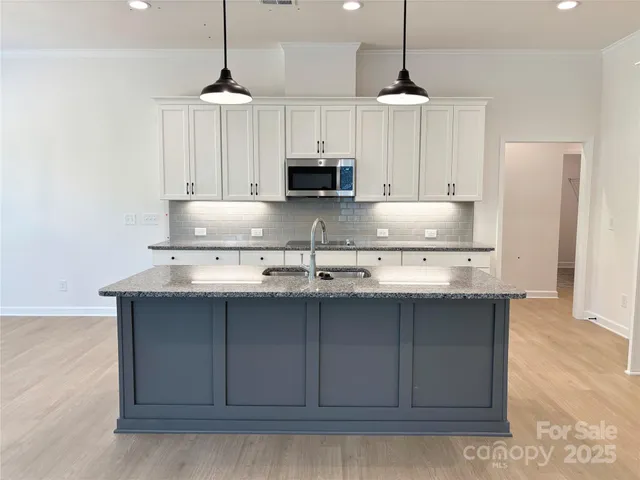 a kitchen with stainless steel appliances granite countertop a sink a stove a refrigerator and white cabinets