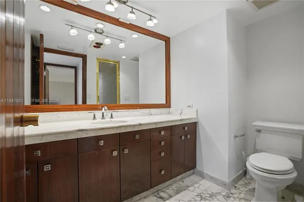 a bathroom with a toilet a double vanity sink and a mirror
