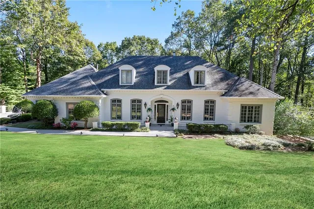 a front view of a house with a garden and trees