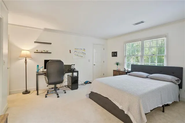 a bedroom with a bed a desk and chair with window