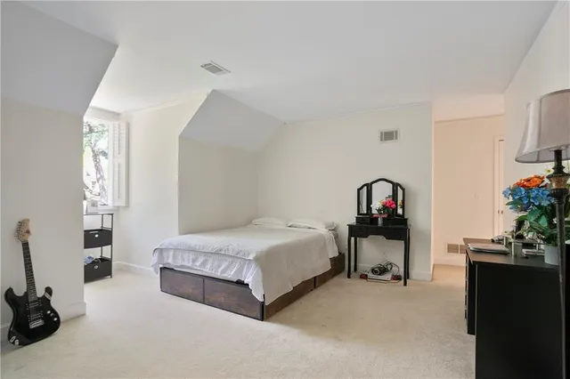 a bedroom with a bed a couch and a flat tv screen on the dresser