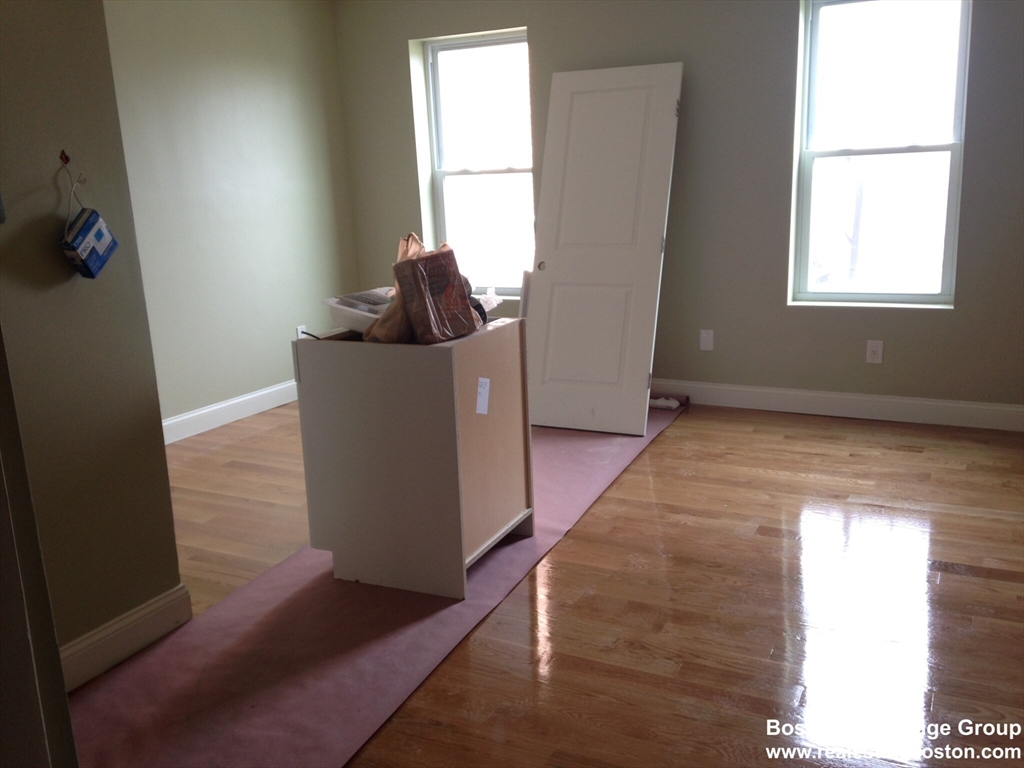 4 Kearsarge Avenue, Unit 2 Boston, MA 02119 - Photo 3 of 6 a view of an empty room with wooden floor and a window