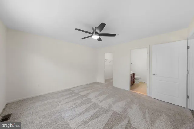 a view of a room with a ceiling fan and carpet