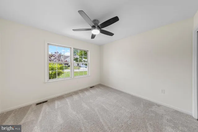 an empty room with ceiling fan and window