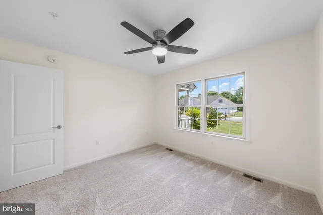 an empty room with ceiling fan and window