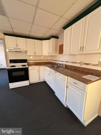 a kitchen with stainless steel appliances granite countertop a stove a sink and white cabinets