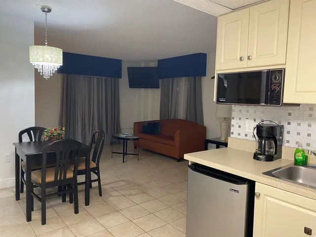 a kitchen with stainless steel appliances a refrigerator a sink a stove a dining table and chairs