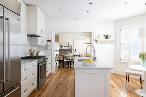 a kitchen with stainless steel appliances granite countertop a refrigerator a stove and a dining table with wooden floor