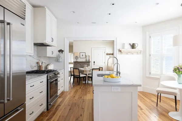a kitchen with stainless steel appliances granite countertop a refrigerator a stove and a dining table with wooden floor