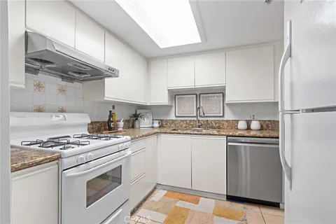 a kitchen with stainless steel appliances granite countertop a stove a refrigerator and a white cabinets