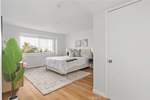 a bedroom with a bed a table and chair with the wooden floor