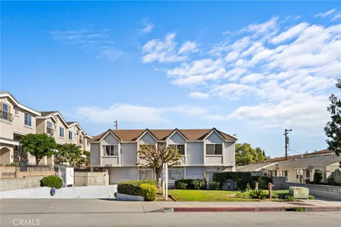 a view of a white house with a large pool and plants