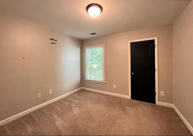 a view of an empty room with window and closet area