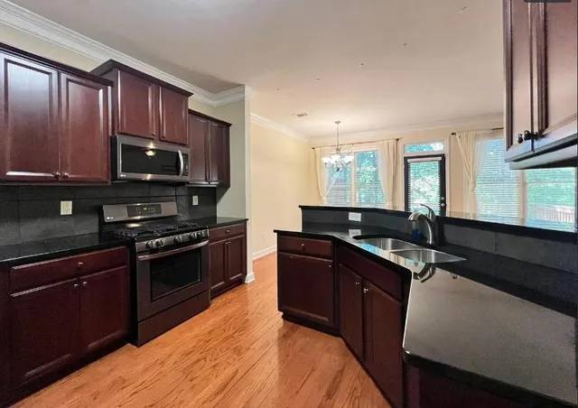 a kitchen with granite countertop wooden cabinets stainless steel appliances and a sink
