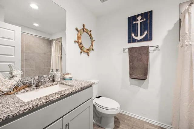 a bathroom with a granite countertop sink mirror vanity and toilet