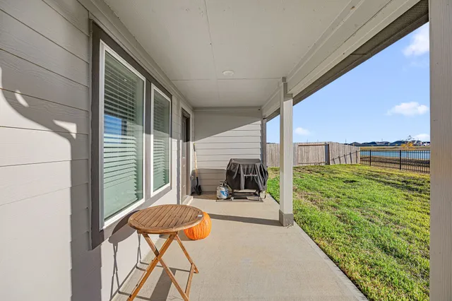 a balcony with table and chairs with wooden floor and fence