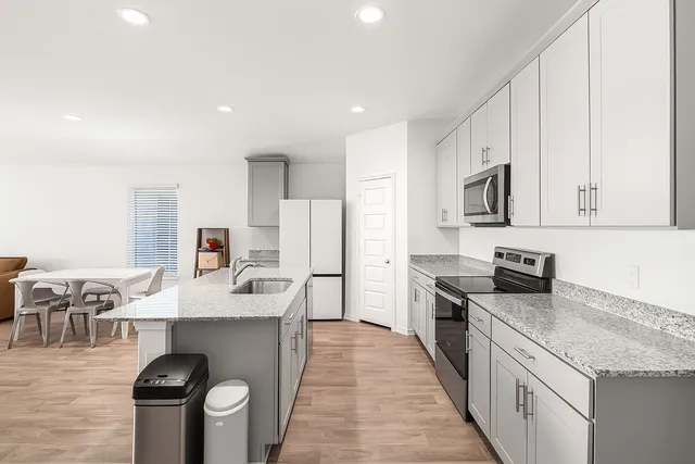 a large kitchen with stainless steel appliances granite countertop a table chairs sink and cabinets