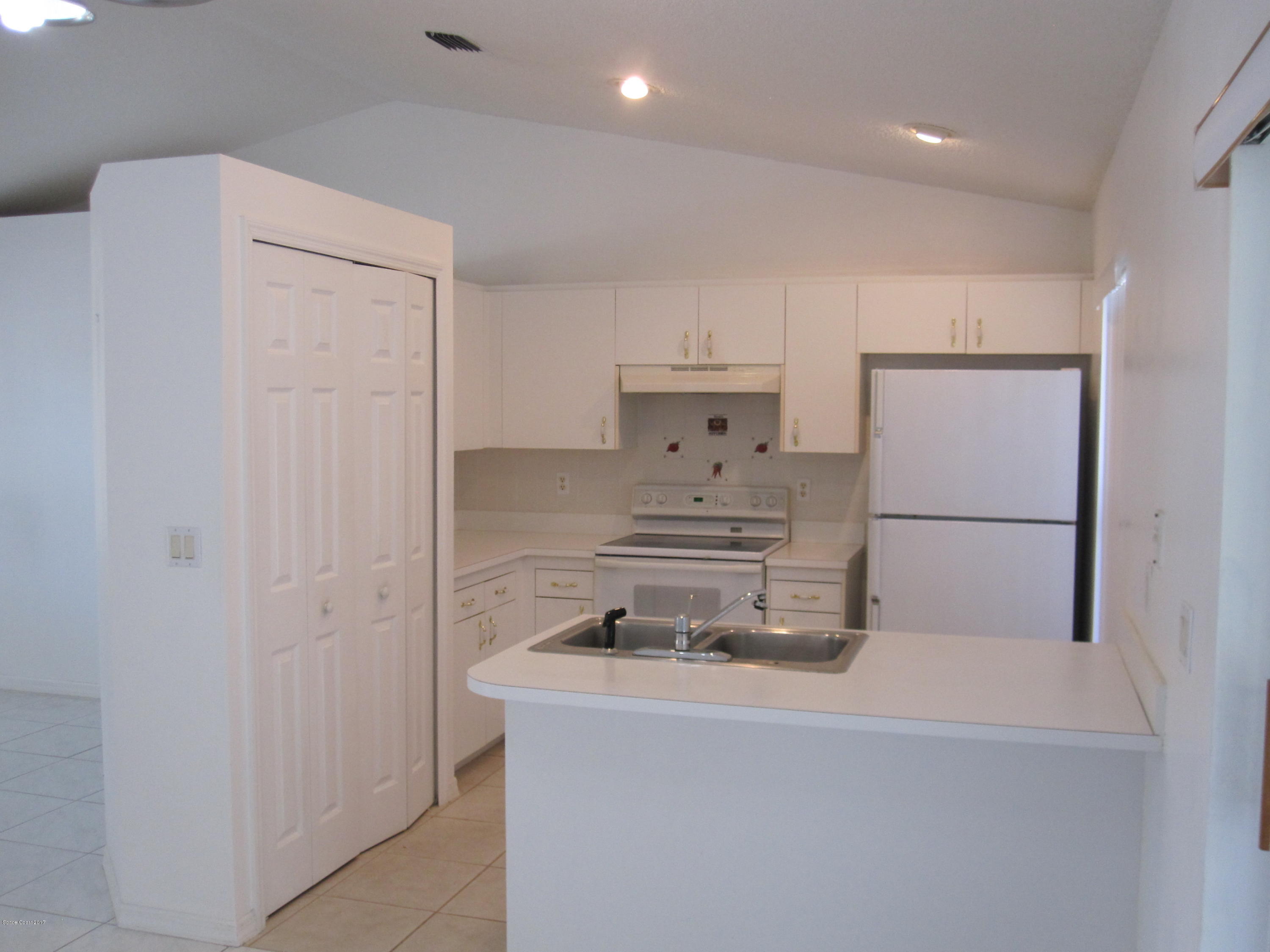 171 Americana Boulevard Northeast Palm Bay, FL 32907 - Photo 7 of 17 a kitchen with a sink a stove and refrigerator
