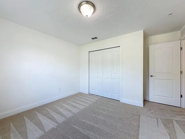 an empty room with wooden floor chandelier fan and windows
