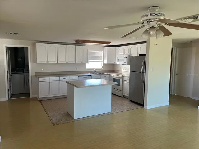 a kitchen with stainless steel appliances granite countertop a refrigerator a sink a stove a microwave and island